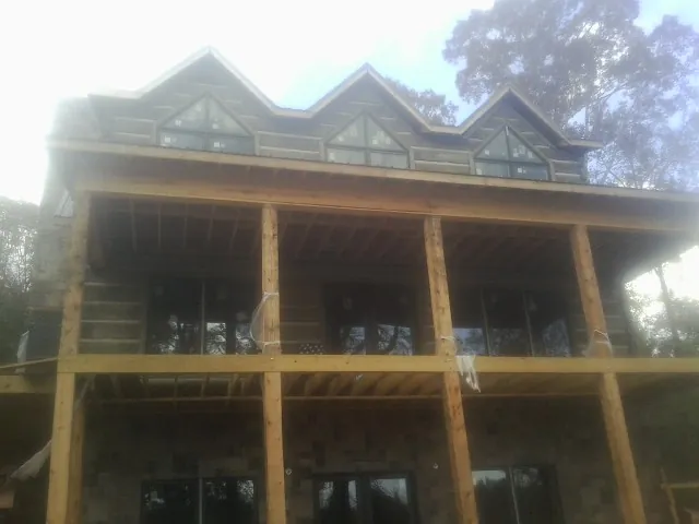 Dormers and porch framing on a large log home under construction — Roof Coating work by our crew in Olar
