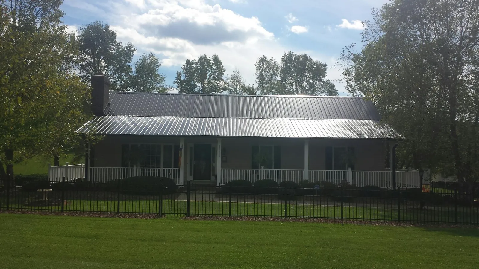 Gray metal roof on a brick ranch with a full width front porch — Gutter Guard Installation work by our crew in Olar