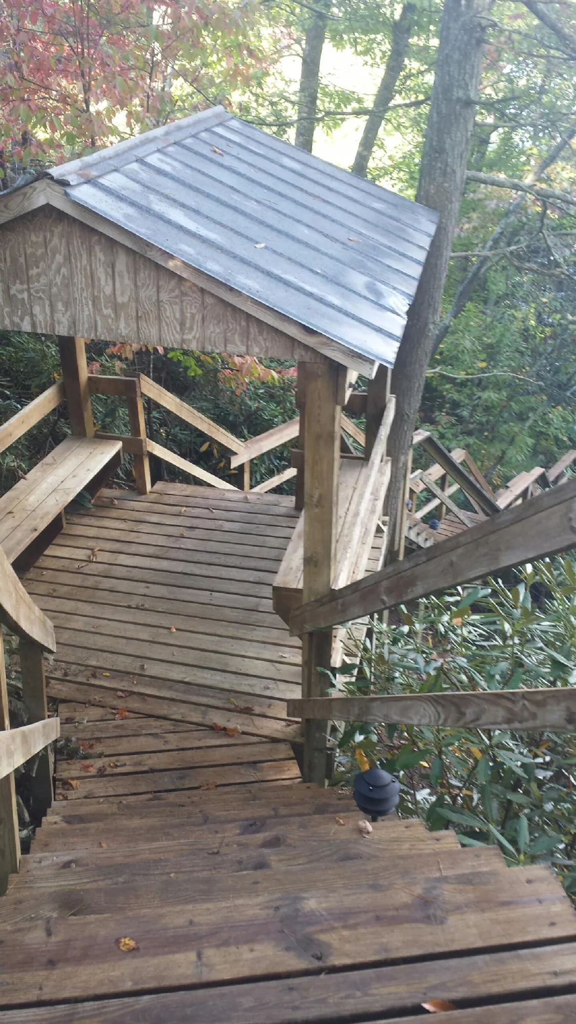 Metal roofed shelter over wooden steps on a wooded walkway — Skylight Repair & Installation work by our crew in Olar